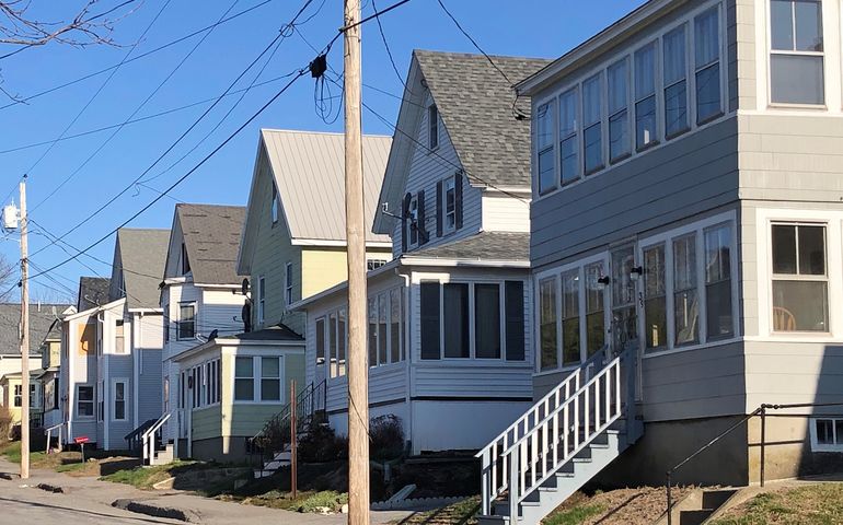 a row of clapboard two and three story apartment houses, close to the street