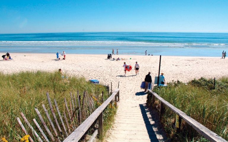 sunlit beach, with stairs leading over dunes in the foreground