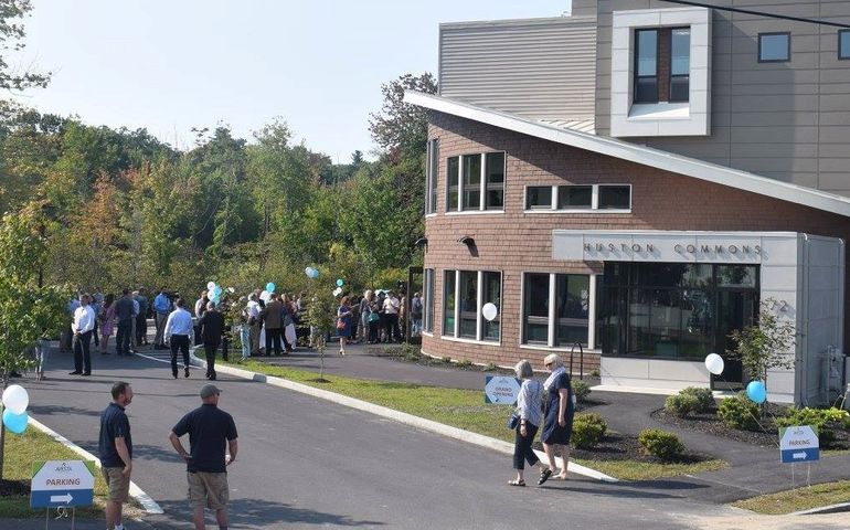 People gather around a building that says Huston Commons 