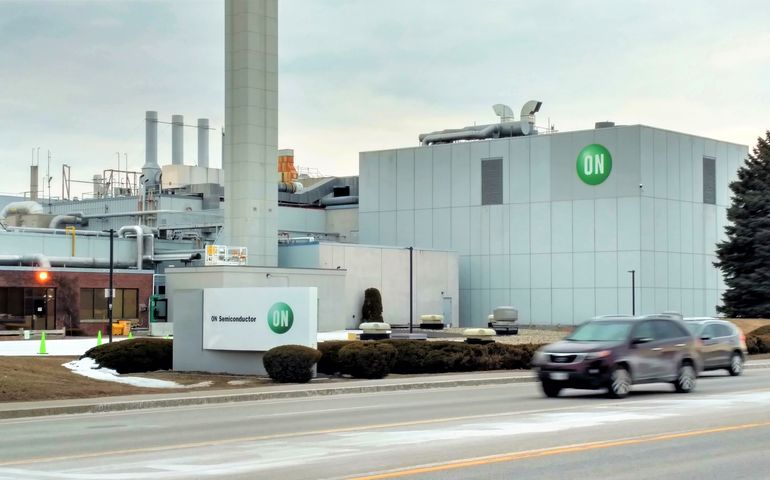 gray, industrial plant with ON sign, viewed from across a street