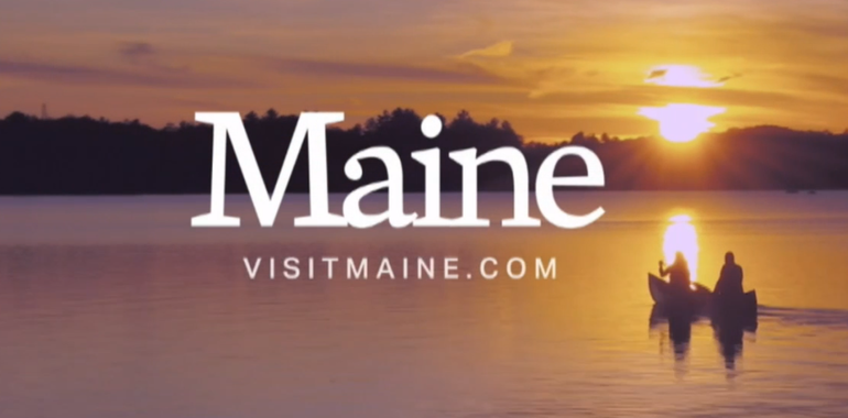 a screenshot of a sunset on a lake with people in a canoe with words that say Maine visitmaine.com