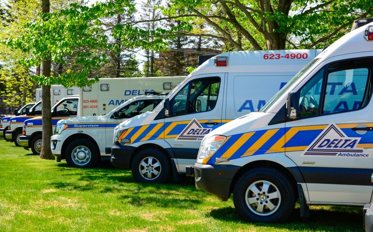 a row of amulances that say Delta on them, parked on a grassy field 