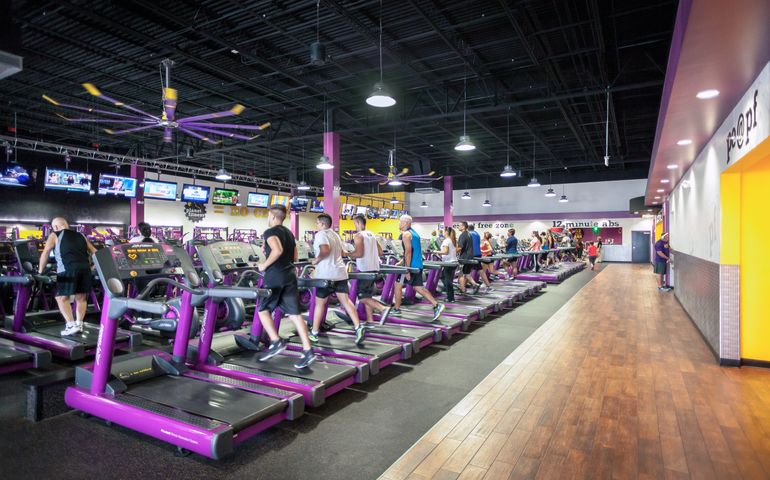 Runners on treadmills inside a Planet Fitness location 