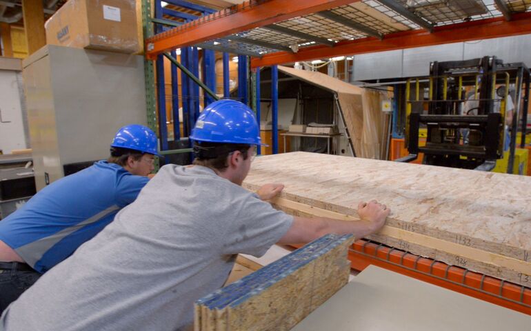 2 people working on wood at machine