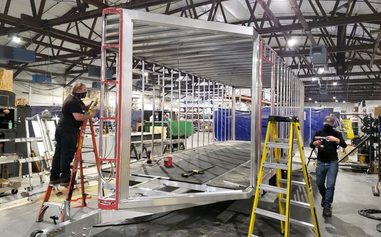 two workers assembling aluminum framework for a trailer