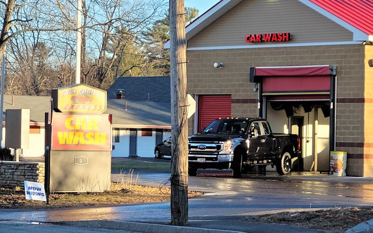 exit of car wash bay, with yellow sign saying fast eddies and black pickup truck