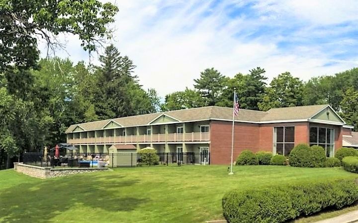 two-story motel surrounded by green lawn, pool and flagpole