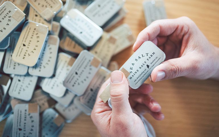 Picture of packages of Maine Salt Farm salt, including one held in two hands. 