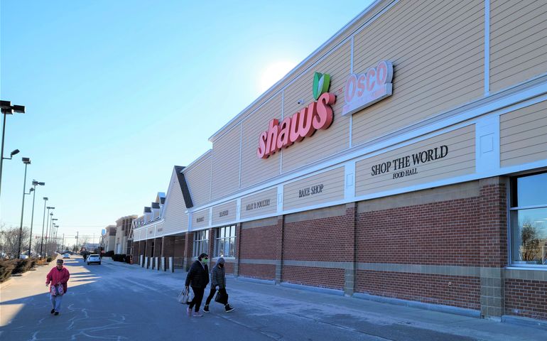 exterior of supermarket with yellow siding and "shaw's" sign