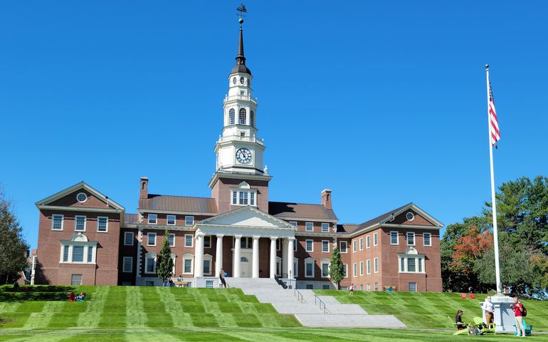 brick building with bell tower and flagpole, students in foreground