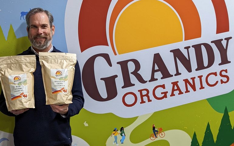 Aaron Anker holding two bags of products showing new company name 