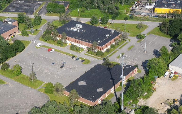 aerial view of two industrial buildings surrounded by trees