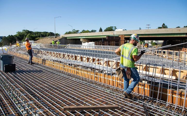 two construction workers on top of a bridge deck covered with rebar