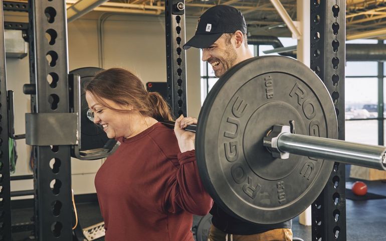 2 people smiling with bar bells