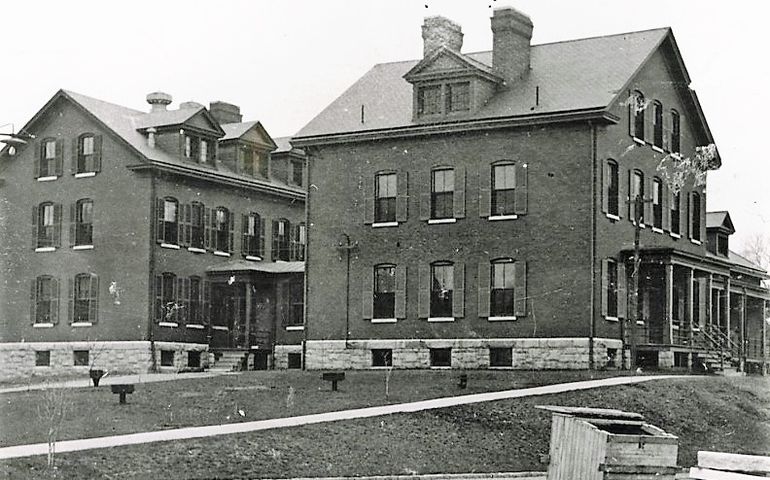 historical B/W image of large, three-story brick building