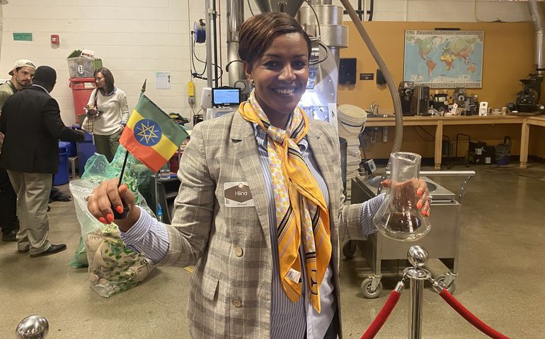 Coffee entrepreneur inside roasters holding up Ethiopian flag 