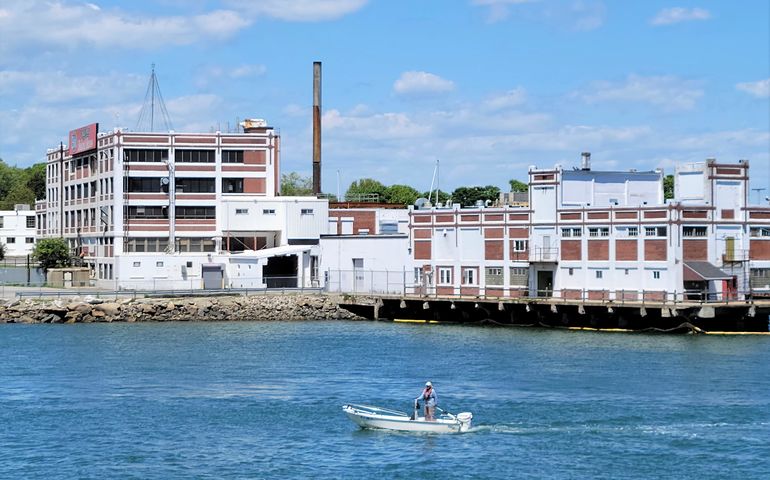 industrial plant on waterfront, with pier and man passing by in a small boat