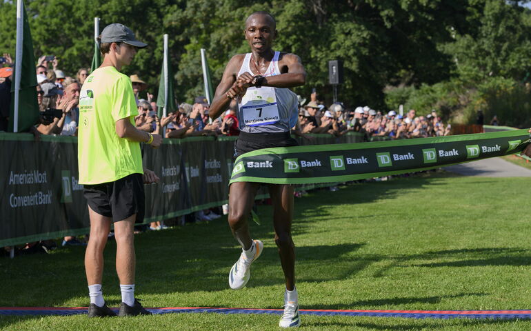 Runner crossing finish line checking watch on wrist 