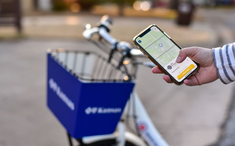 hand holding a smart phone nexts to bike-share bike 