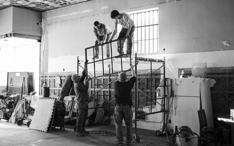 4 people and scaffolding inside building