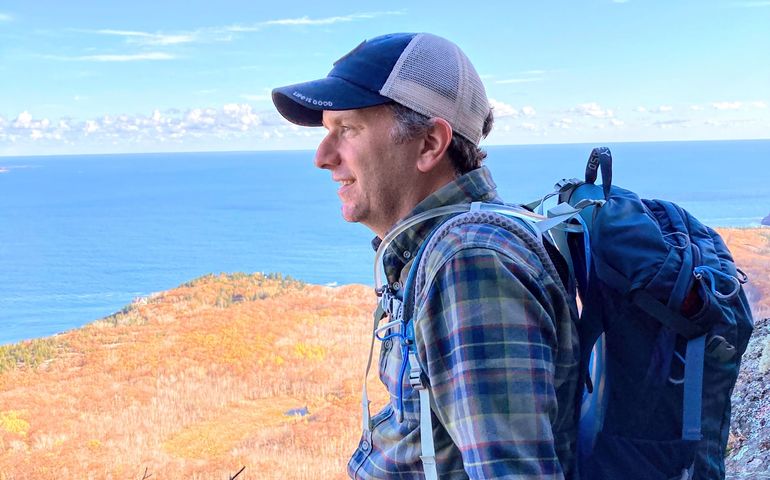 person in ballcap with knapsack overlooking harbor