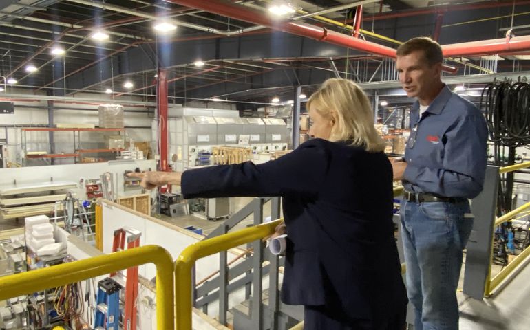 Mills at a factory with another person