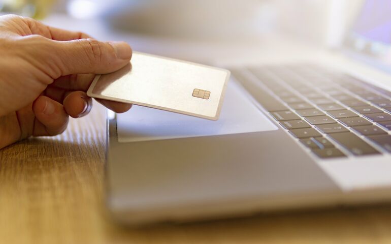 Hand with credit card and a laptop computer 