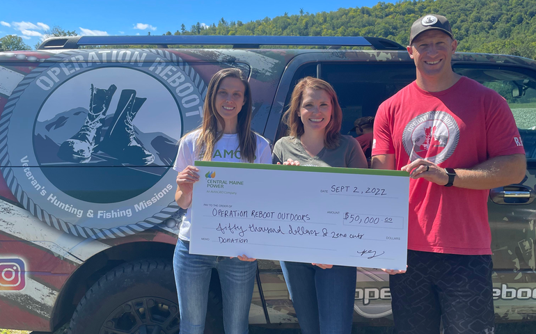 Three people standing with oversized donation check
