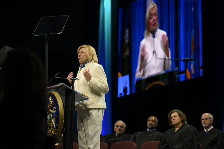 Mills at podium with judges to her side