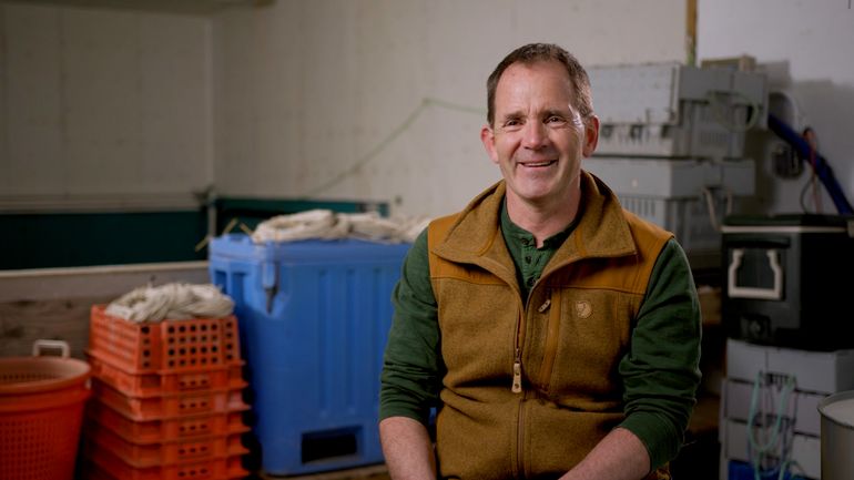 person smiling in vest with seafood totes