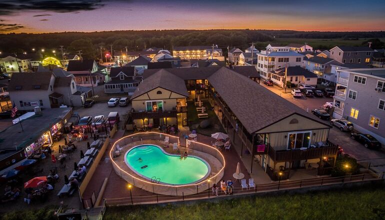 motel with lit pool at dusk in aerial shot