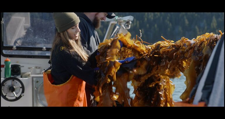2 people with lines of seaweed on boat