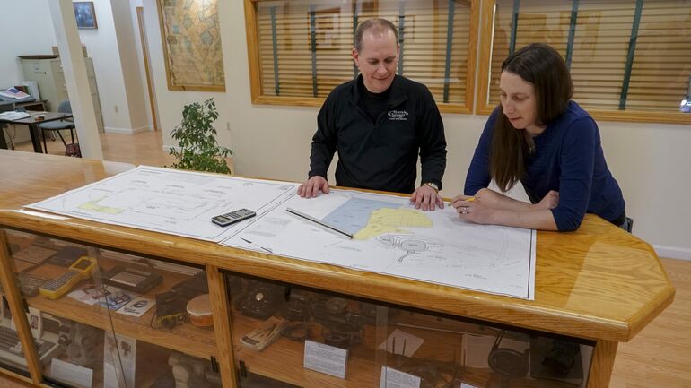 2 people at long wood table with drawings