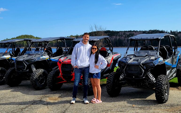 2 people standing with ATVs