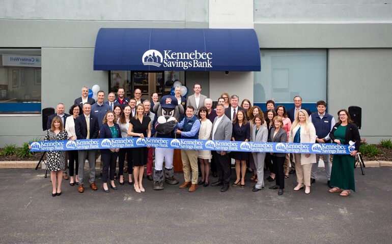 big group of people in front of building with ribbon