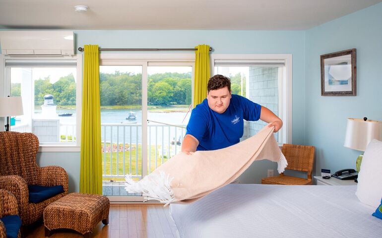 Person making bed in a hotel room