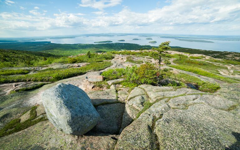 granite boulders on hilltop with harbor in the distance