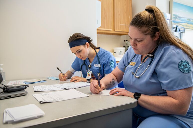 2 people in blue scrubs writing