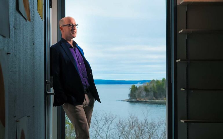 person in purple shirt and blazer standing at large window