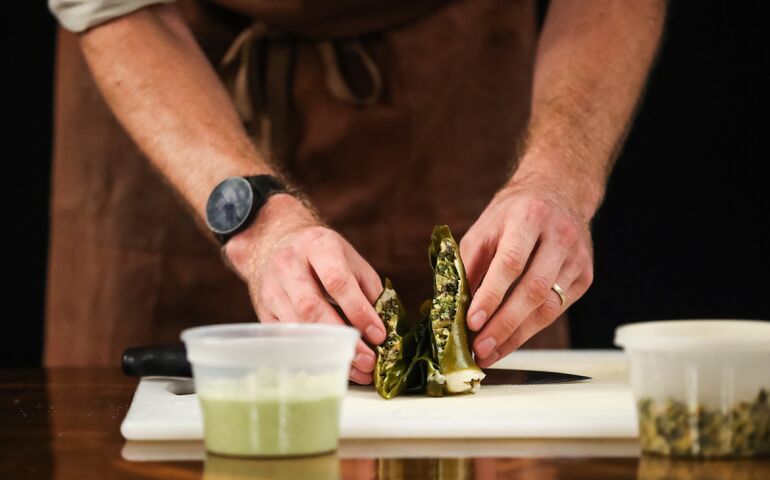 person's hands with food and cutting board