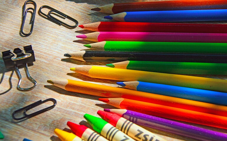 Crayons, colored pencils and paper clips on a desk 