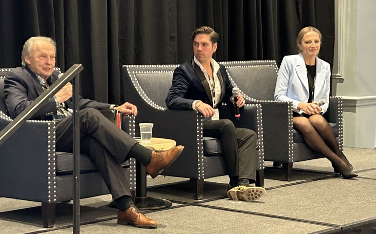 Three people seated on stage 