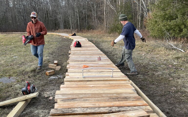 2 people with planks on boardwalk