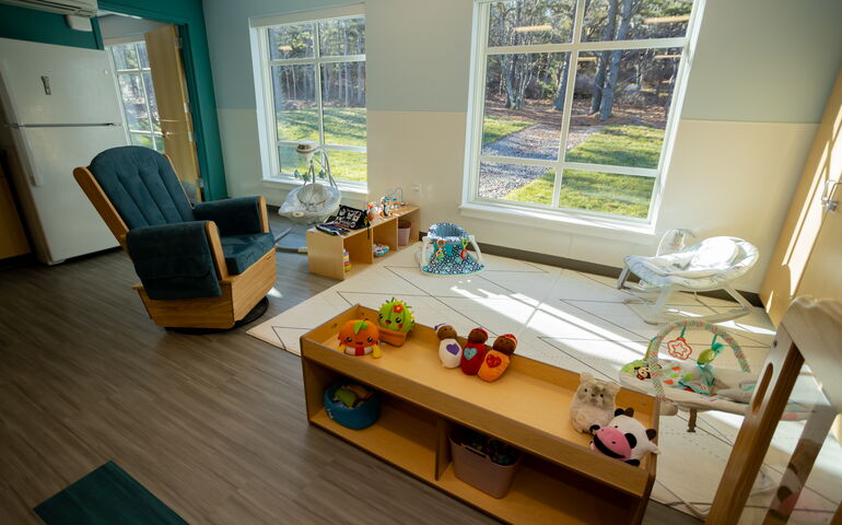 inside a room with chair and shelves and window