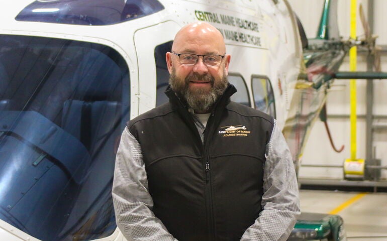 person in vest standing in front of helicopter