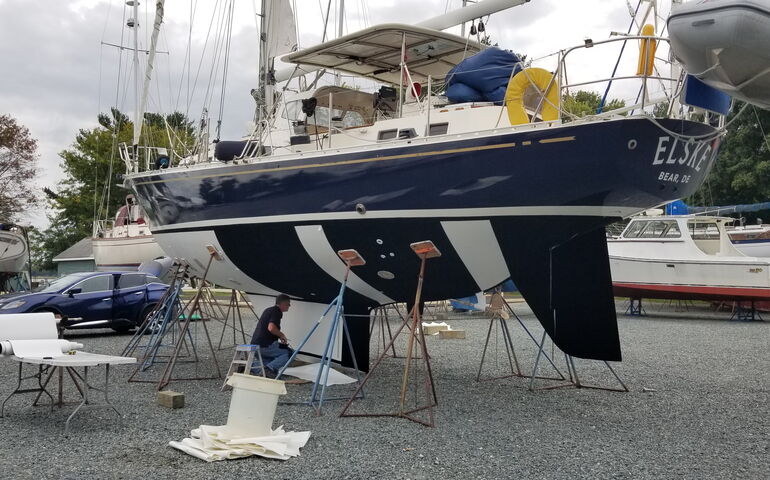 boats on jackstands and person under one boat