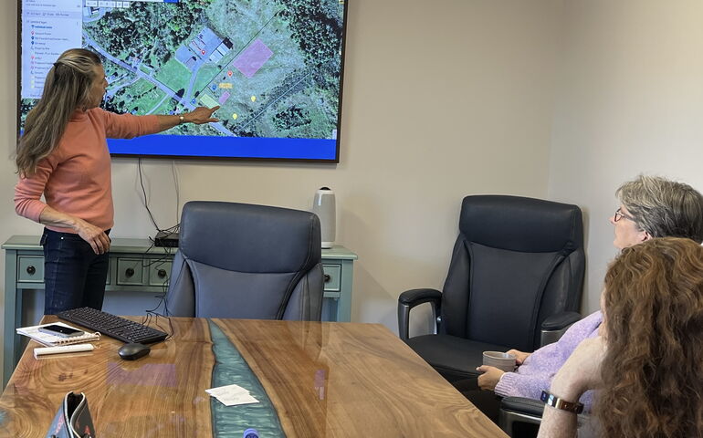 person in a conference room pointing at a map on the wall 