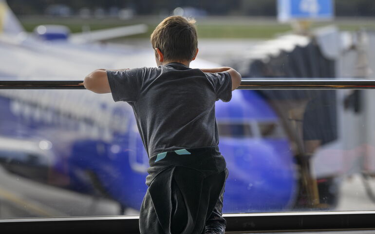 boy at airport looking at airplane 