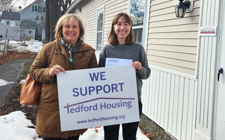 2 people standing and holding sign