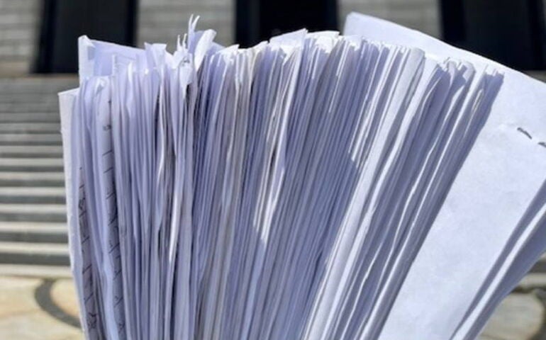 A sheaf of papers is positioned against backdrop of a building.